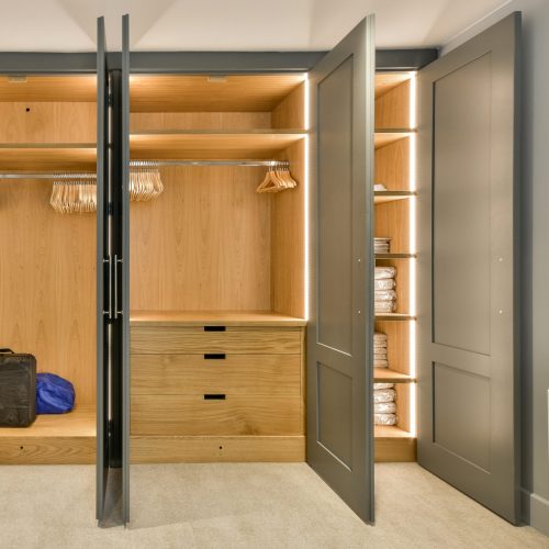 a walk - in closet with clothes hanging on the wall and an open door that leads to a bathroom area